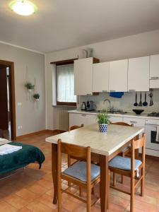 a kitchen with white cabinets and a wooden table and chairs at Mimì apartment - Vicino a Gardaland in Peschiera del Garda