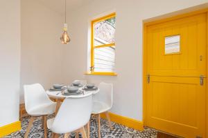 a dining room with a yellow door and white chairs at Host & Stay - Temple Gardens in Lincoln +6 photos