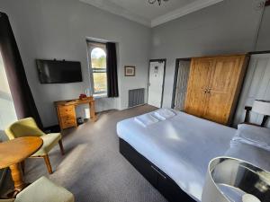 a bedroom with a bed and a table and a television at The Sun Inn in Troutbeck Bridge