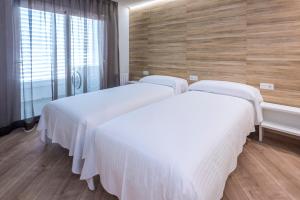 2 camas con sábanas blancas en una habitación con ventana en Mònica Mar Apartments, en Cambrils