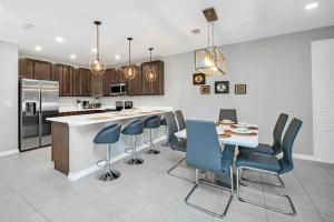 a kitchen with a table and some blue chairs at SUPER BOHO CHIC Stylish Blend NEAR Disney in Kissimmee