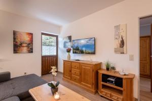 Una sala de estar con un sofá y un televisor en la pared. en Bergschlössl Whg 3, en Oberaudorf
