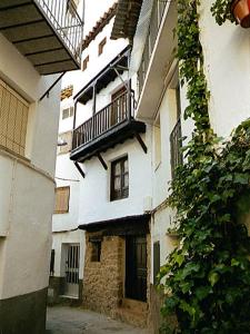 un callejón con un edificio blanco con balcón en Casa Rural La Cueva, en Casas del Castañar