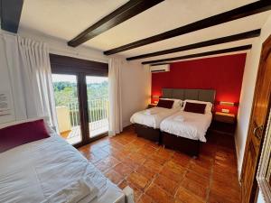 a bedroom with two beds and a red wall at Secrets Rural House in Jávea +47 photos