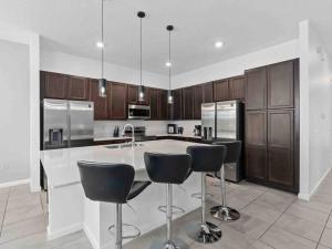 a kitchen with a island with bar stools and stainless steel appliances at SUPER JUMBO - 12BD 12BAs SLEEPs 34 - w AMENITIEs in Kissimmee