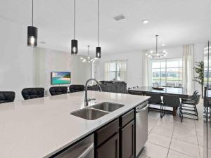 a white kitchen with a sink and a table at SUPER JUMBO - 12BD 12BAs SLEEPs 34 - w AMENITIEs in Kissimmee +56 photos
