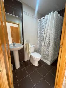 a bathroom with a white toilet and a sink at Precioso piso familiar in Daimiel