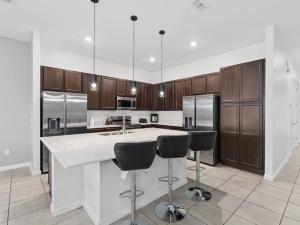 una cocina con una gran isla blanca con taburetes de bar en SUPER SPACE - 12BD 12BA - MANY ENSUITEs SLEEPs 38, en Kissimmee 57 fotos más