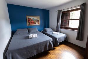 Habitación azul con 2 camas y ventana en Refúgio Alpino Economy, en Campos do Jordão 27 fotos más