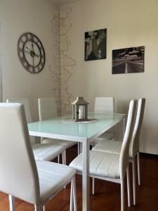 a dining room table with white chairs and a clock at MaMà - Ma Maison d'Hotes in Vigliano Biellese