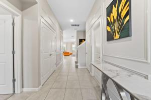 a hallway with white walls and a painting on the wall at SUPER LARGE - 12BD 12BAs - MANY ENSUITEs SLEEPs 30 in Kissimmee