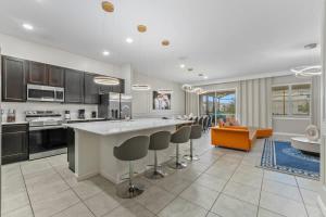 a kitchen with a large island with bar stools at SUPER LARGE - 12BD 12BAs - MANY ENSUITEs SLEEPs 30 in Kissimmee +64 photos