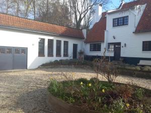 Casa blanca con techo rojo y patio en Bed and Breakfast Ros & Marc en Wezembeek-Oppem