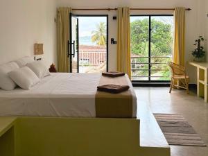 a bedroom with a large bed with a large window at Calma - Surf, Yoga & Coffee on a Private Beach in Dickwella