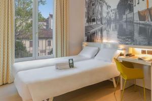 1 dormitorio con cama, escritorio y ventana grande en B&B Hotel Treviso, en Treviso