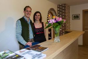 a man and woman standing next to a table with flowers at Weingut - Gästezimmer Resch Ludwig vlg. Powoden in Leutschach