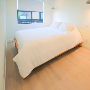 a white bed in a room with a wooden floor at Newly Renovated 2 Bedroom Condo in Japantown! Near Railtown & Gastown! in Vancouver