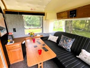 ein Wohnzimmer mit einem schwarzen Sofa und einem Holztisch in der Unterkunft Bonny Airstream in Inver Mallie + 37 Fotos