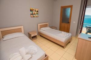 two beds in a room with a view of the ocean at Fly Hotel in Vlorë