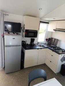 a small kitchen with a refrigerator and a sink at Mobil Home 3 chambres in Ouistreham +16 photos