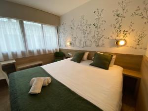 a bedroom with a large bed with two towels on it at The Originals City, Le Patio Hôtel, Cholet Nord in Beaupréau