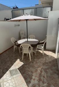 a table and chairs with an umbrella on a patio at Casa Vacanza Delfino in Porto Cesareo