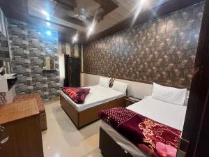 a bedroom with two beds and a wall with a mural at Hotel Aapno Shyam And Restaurant in Khātu +26 photos