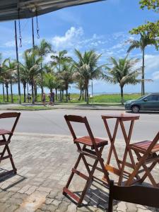 two chairs and a table on a patio with palm trees at Apartamento perto do mar com garagem coberta em Praia de Leste in Pontal do Paraná