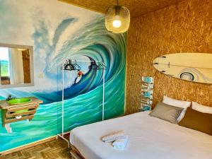 a bedroom with a painting of a surfboard on the wall at Eco Hostel - Tribo da Praia in Ferrel