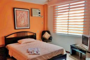a bedroom with orange walls and a bed and a television at Casa Palmare in Manta
