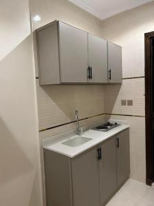 a kitchen with a sink and white cabinets at فندق النخبة الماسي - Diamond Elite Hotel in Al Madinah