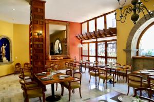 a dining room with tables and chairs and a mirror at Hotel de Mendoza in Guadalajara