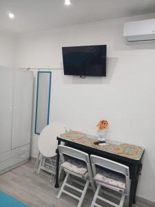 a room with a table with chairs and a tv on the wall at Green Garden da Virna 2 in Torre Annunziata