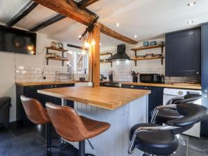 a kitchen with a wooden counter and stools at Bedfordshire Thatched Cottage - Dogs Welcome in Bedford +15 photos
