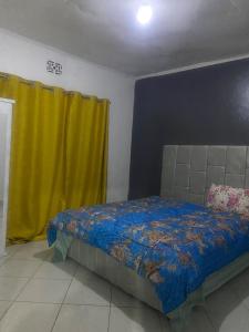 a bedroom with a bed and a yellow curtain at Mila home in Arusha +2 photos