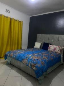 a bedroom with a bed and yellow curtains at Mila home in Arusha