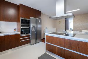 uma cozinha com armários de madeira e eletrodomésticos de aço inoxidável em The Povoa Villa na Póvoa do Varzim