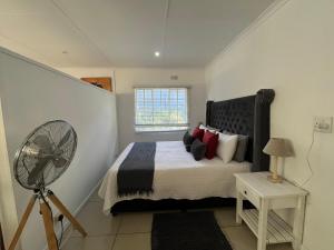 a bedroom with a bed with a fan and a window at A cozy cottage in Bryanston in Sandton