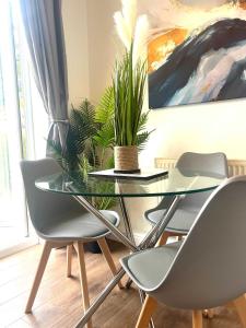 a glass table with four chairs and a plant on it at The Billingham House By Blue Skies Stays in Stockton-on-Tees