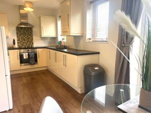 a kitchen with white cabinets and a glass table at The Billingham House By Blue Skies Stays in Stockton-on-Tees +13 photos