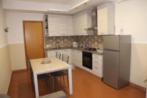 a kitchen with a table and a refrigerator at La Casetta per te in Gravina di Catania