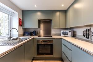 eine Küche mit grauen Schränken und einer Spüle in der Unterkunft Wallaby - East Wittering Fisherman's Cottage in East Wittering