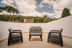 two chairs and a table with a picture on the wall at Apartamento Le Neuf Centro in Monte Verde