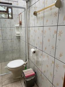 ein Bad mit einem WC und Blumen an der Wand in der Unterkunft Cantinho da serra do Guaraú in Peruíbe