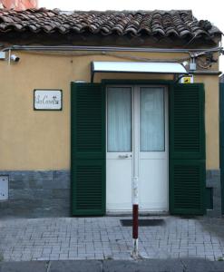 a building with green doors and a sign on it at La Casetta Per Te in Gravina di Catania