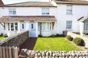 ein weißes Haus mit einem Steinzaun und einem Hof in der Unterkunft Wallaby - East Wittering Fisherman's Cottage in East Wittering