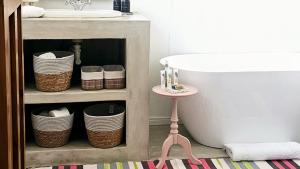 a bathroom with a sink and a table next to a bath tub at Grey Rabbit Cottage in Montagu +36 photos