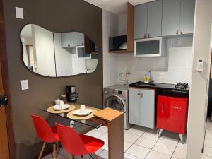 een kleine keuken met een tafel en rode stoelen bij Loft moderno e aconchegante próximo ao Aeroporto, Rodoviária Interestatual, P Federal, Casv da Empaixada - Brasília in Brasilia