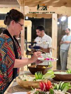 a woman holding a plate of food at a buffet at Diamond luxury rum in Wadi Rum +68 photos