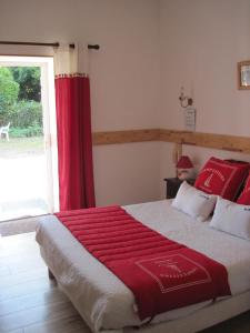 a bedroom with a large bed with a red curtain at Le Relais de Porz Morvan in Plomodiern